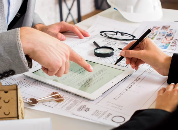 Two professionals reviewing a tablet with contractor payment and 1099 documents.
